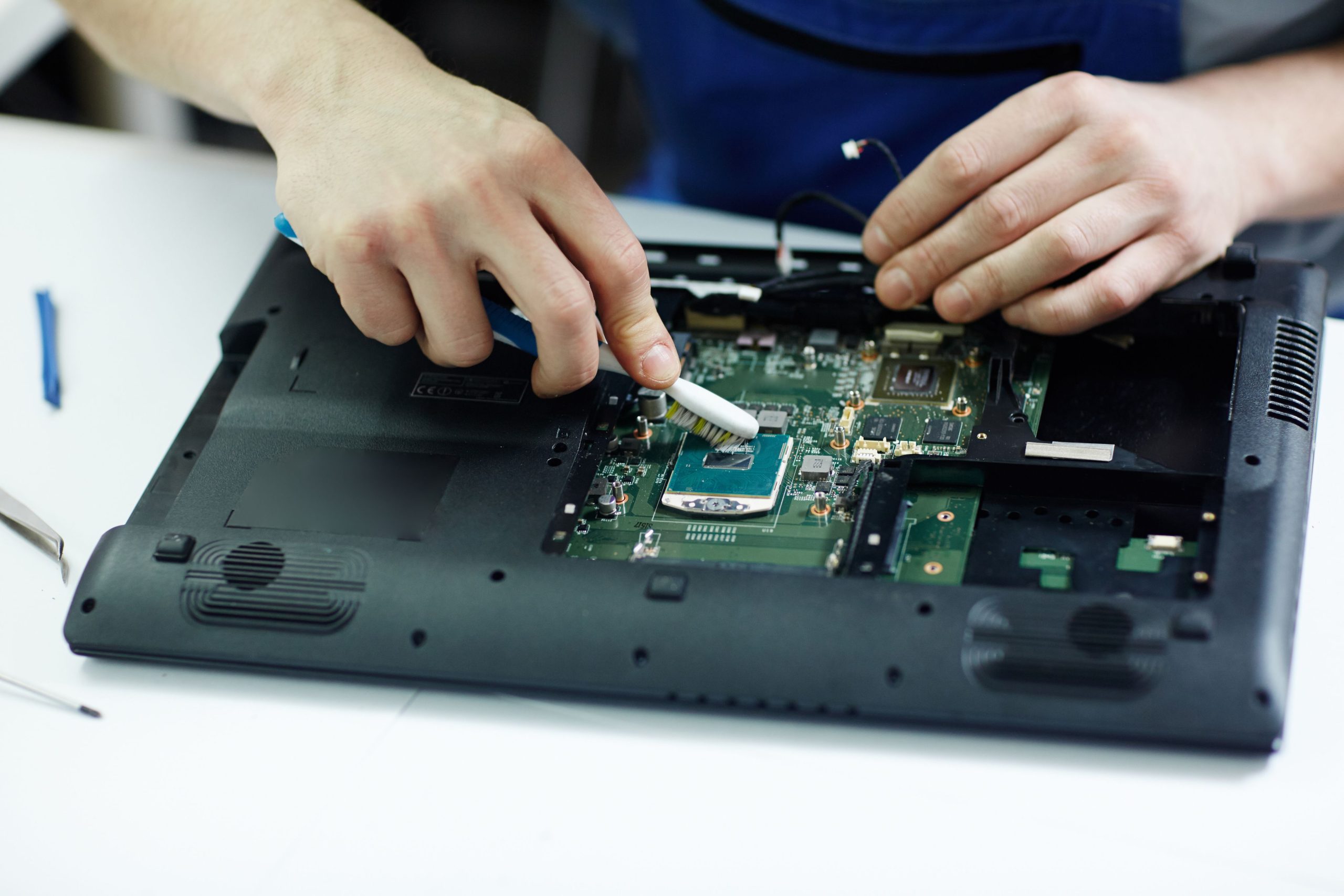technician-clearing-circuit-board-disassembled-laptop (1)